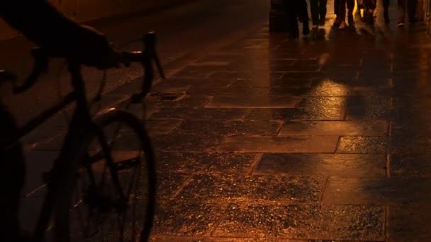 クラスアップ 雨の夜に輝く湿った舗装を歩いている都市の人々のフィート 暗い夜の街路や車のライトからの光を反射するコブストーンパターンの光沢のあるウェットウォーク表面 — ストック動画