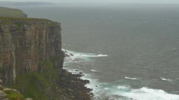 成群的海鸟环绕在岩石悬崖峭壁上 在多风的天气里寻找栖身之处 数百只海鸥和海雀乘着大风航行 刮来的大风刮向苏格兰最北岸的风景 — 图库视频影像