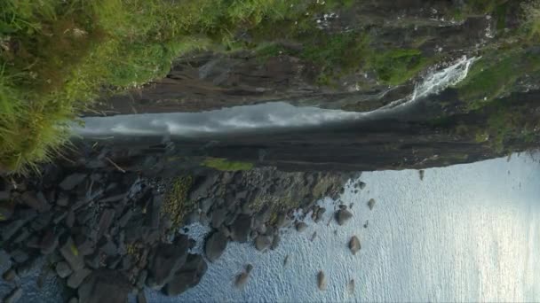 美丽的大瀑布从长满青草的悬崖上落下来 落在布满花岗岩石的岩石海岸上 斯凯岛上著名的内斯特角附近有着崎岖海岸线的令人叹为观止的风景 — 图库视频影像