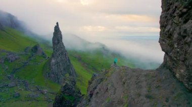 Kadın, puslu Katedral Kayası 'na hayran olduğu bakış açısına tırmandı. Genç maceracı, Skye Adası 'ndaki pitoresk dramatik manzarayla benzersiz doğal cazibeleri keşfediyor..