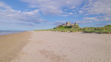 Muhteşem Bamburgh Şatosu kumlu plajın üzerinde yükselen bir uçurumun üzerine inşa edildi. Kuzey Denizi kıyısında ünlü kalesi olan nefes kesici kıyı manzarası. Çarpıcı bir turistik cazibe tarihe karıştı..