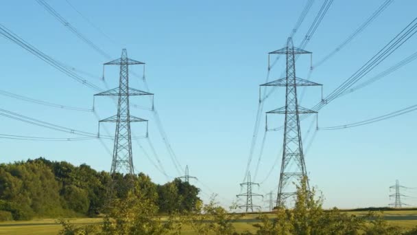 イギリスの田舎にある発電所付近の高圧送電線 多数の鋼鉄塔およびケーブルが付いている産業構造は大きい間隔に電気エネルギーの配分をします — ストック動画