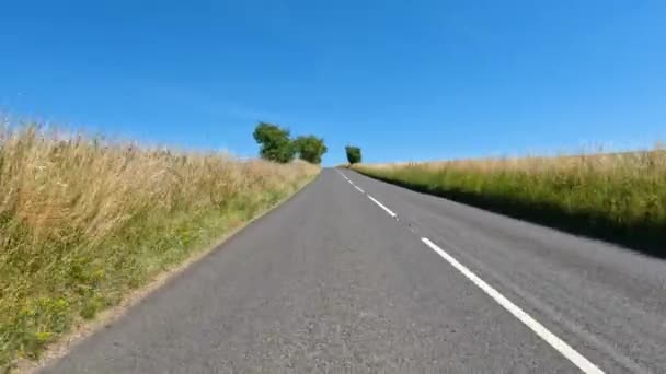 明確な青空の下でイギリスの田舎を介して国道を運転する車 晴れた夏の日の絵のように広がる緑の牧草地や牧草地を旅する — ストック動画