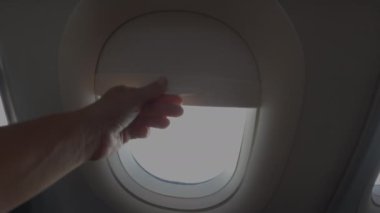 Uçak yolcusu uçuş sırasında uçak penceresinin perdesini kaldırır. Alman manzarasının üzerinde, uçak kanadının ve kabarık bulutların görüntüsü. Uzak yerlere gitmek için modern ulaşım araçları.
