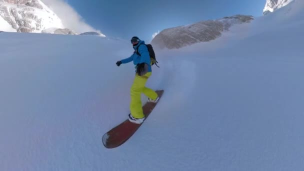 スノーボードに乗った若者は 雪だるまの山を降りる ホワイトパウダーの雪は 恐怖のないスノーボーダーが急な斜面を回すように周りを飛んでいます アルプスの美しい冬の日 — ストック動画