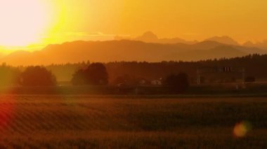 AERİAL, LENS FLARE: Altın batan güneş manzaralı Slovenya kırsalını geçen otoyol trafiğini aydınlatıyor. Sabah banliyöleri gün doğumunda altın ışıklı otoyolda ilerliyorlar..