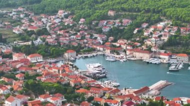 Hırvatistan 'ın Hvar adasının yemyeşil körfezindeki geleneksel bina ve yatların insansız hava aracı görüntüsü. Bereketli yeşillik ve sakin deniz arasında bir marinası olan tuhaf bir sahil kasabası olan Hvar..