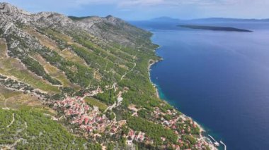 AERİAL Bir hava manzarası Adriyatik 'i kucaklayan büyüleyici bir kıyı köyünü gözler önüne seriyor, tepe yamacında teraslı üzüm bağları bulunuyor. Hvar adasındaki tuhaf bir sahil kasabası Dalmaçya sularına bakıyor.