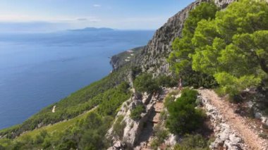 Aktif dişi turist köpeğiyle birlikte engebeli Akdeniz adasında yürüyüş yapıyor. Hvar adasının yürüyüş yollarını keşfeden bir kadın köpek yavrusu Adriyatik Denizi 'ne bakan bir patika boyunca yürüyor.