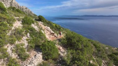 Kadın, Adriyatik Denizi 'ne bakan bir patika boyunca köpek yavrusuyla Hvar adasının yürüyüş yollarını keşfediyor. Akdeniz 'in engebeli adasında köpeğiyle gezen aktif dişi turist.