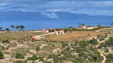 Adriyatik denizi ve uzaktaki dağları gören Hvar adasının tepesindeki uzak bir çiftliğin panoramik görüntüsü. Kırsal çiftlik, derin mavi Akdeniz 'in pitoresk bir manzarasını sunuyor