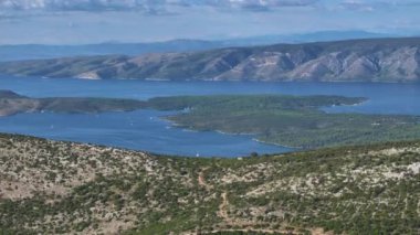 Uçsuz bucaksız, bulutlu gökyüzünün altındaki kayalık arazi, sakin Adriyatik Denizi 'ne dökülüyor. Sütyen adası ve anakara Hırvatistan Hvar 'ın tepesinden görülüyor