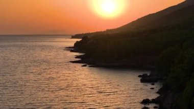 Güneşli bir yaz akşamında Hvar adasının engebeli bir kıyısının manzarası. Adriyatik Denizi 'nin sakin sularının altın saatinde nefes kesici manzarası. Gündoğumunda Dalmaçya 'daki Idyllic Adası.