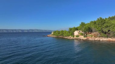 Hvar 'daki uzak bir sahilde çürüyen iki binayı çevreleyen bereketli Akdeniz bitkisinin insansız hava aracı görüntüsü. Adriyatik Denizi kıyısında terk edilmiş bir ev ve şapel..