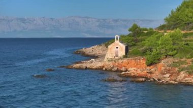 Hırvatistan 'ın Hvar adasındaki ıssız bir kayalık kıyının kıyısındaki çürüyen bir şapel boyunca uçmak. Akdeniz 'de sakin, ıssız bir adanın sahilindeki küçük eski bir şapelin fotojenik bir fotoğrafı..