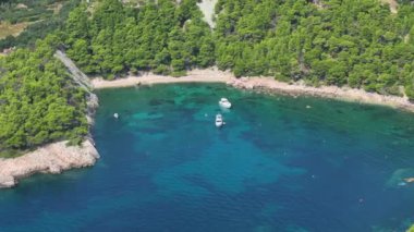 Hvar adasındaki engebeli, ıssız bir sahilin sahili ve birkaç demir atmış tekne. Denizde yalnız bir kürekçi sıcak yaz gününün tadını çıkarır. Kıyı yemyeşil..