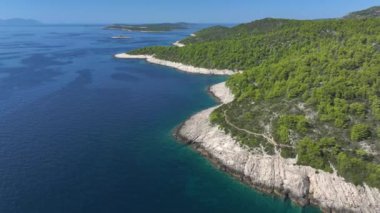 Adriyatik adası Hvar 'ın engebeli kayalık bir kıyı şeridi boyunca uçuyor. Uçsuz bucaksız mavi deniz ufukta ve vahşi takımadaların arasında uzanır. Hvar adasının uzak bir köşesinde çekilmiş..