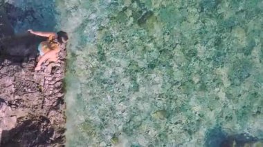 Genç bir kadının parlak turkuaz suya dalışının, su sıçratışının görüntüsü. Su dibe kadar temiz ve Hırvatistan 'da sıcak bir yaz gününün güneşinde ışıldıyor