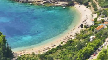 Turkuaz denize bakan koltuklarıyla kumlu bir plajın üzerinde uçmak. Turistler Hvar adasının kıyılarındaki yaz etkinliklerinin keyfini çıkarıyorlar. Yazın Dalmaçya 'nın insansız hava aracı görüntüsü.
