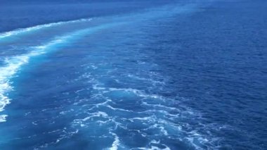 Deep blue sea stretches out behind a ferry, its wake creating foaming waves, encapsulating the sense of movement and tranquil mood of a sea voyage. Ferry ride to Korcula island on calm Adriatic sea.