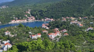 Hırvat adasındaki sahil evlerinin altındaki küçük bir kasabanın insansız hava aracı görüntüsü. Akdeniz kıyısı boyunca uçuyor ve Korcula adasının uzak bir köşesinde uykulu bir okyanus köyü var..