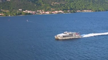 KORCULA ADASI, KROATIA, 5 Mayıs 2024, AERIAL: Büyük mavi Adriyatik denizi, çarpıcı Korcula adası yakınlarında yelken. Akdeniz 'de toplu taşımacılık yapan bir katamaranın insansız hava aracı görüntüsü.