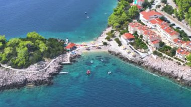 Turistler Korcula adasının kıyılarındaki yaz etkinliklerinin tadını çıkarıyorlar. Turkuaz denize bakan koltuklarıyla kumlu bir plajın üzerinde uçuyorlar. Yazın Dalmaçya 'nın insansız hava aracı görüntüsü