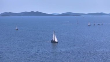 Dalmaçya 'da güneşli bir yaz gününde sayısız yelkenli derin mavi denizlere yelken açar. Büyük bir yelkenli yarışı sırasında Adriyatik denizinin manzarası. Murter yakınlarında yaz gezginleri
