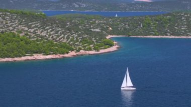 Murter Adası yakınlarındaki manzaralı sularda yelken açan bir yelkenlinin sinematik drone görüntüsü. Lüks yelkenli, güneşli bir günde Adriyatik 'in sakin sularını keşfeder. Eğlenceli yaz tatili aktivitesi