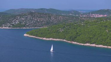 Güneşli bir yaz gününde Murter adasının kıyılarını keşfeden yalnız bir yelkenlinin üzerinde uçmak. Adriyatik Denizi 'ndeki güzel bir adanın panoramik manzarası..