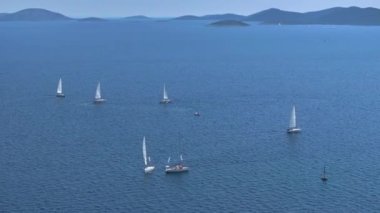 Güneşli bir yaz gününde sakin Adriyatik sularında sayısız yelkenlinin üzerinde uçmak. Hırvatistan 'ın Murter Adası yakınlarındaki açık denizlerde yelkenlilerin panoramik drone görüntüleri. Yaz tatili etkinliği