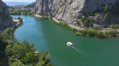 Güneşli bir günde Zümrüt Çetina nehri boyunca gezi teknesi yelken açar. Her iki nehir kıyısında yüksek kayalık uçurumları olan yemyeşil bir nehir geçidi boyunca boş bir tekne dolaşır. Hırvatistan 'ın doğal güzelliği.