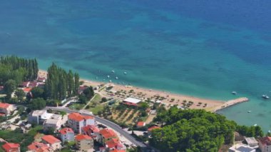 Kumlu sahil ve renkli deniz olan tuhaf sahil kasabasının yerleşim alanının insansız hava aracı görüntüleri. Omis 'in deniz kıyısındaki gayrimenkullerinin üzerinde uçarken nefes kesen turkuaz renkli Adriyatik Denizi' ne bakıyor..