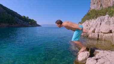 Aktif turist başını önce yükseltilmiş bir kayadan güzel bir ada körfezindeki inanılmaz açık mavi okyanusa doğru kaldırır. Yaz tatili boyunca güneşli günler için hoş bir içecek.