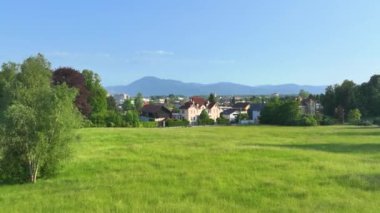 Rüzgarda dalgalanan Amerikan bayrağına sahip görkemli bir villa, arka planda yükselen dağlarla çevrili Ljubljana kasabasının eteklerinde sessiz, yemyeşil bir sokakta övünüyor..