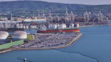 KOPER PORT, SLOVENIA - 3 Mart 2024: AERIAL: güneşli bir ilkbahar günü meşgul Koper limanının panoramik insansız hava aracı görüntüsü. Kargo ve yük gemilerinin hava görüntüsü.