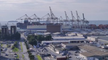 KOPER PORT, SLOVENIA - 3 Mart 2024: AERIAL: Luka Koper 'in depolama tesisleri ve vinçleri üzerinde uçuyor. Uzaktaki yük gemileri Koper limanına yaklaşıyor. Slovenya 'daki ticaret merkezi