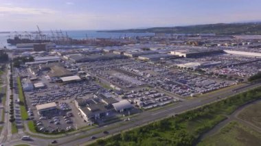 KOPER PORT, SLOVENIA - 3 Mart 2024: AERIAL: Rıhtımlı yük gemileri ve sanayi limanı otoparkına park etmiş büyük araba filosuyla Luka Koper 'ın insansız hava aracı görüntüsü.