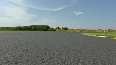 Güneşli bir yaz gününde kırsal alanda boş bir yarış pistinde araba sürmek. Eğlenceli bir pistte boş bir yarış pistinde sürerken yüksek hızlı çekim. Motorsporu hobisi