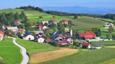 Güneşli bir yaz gününde yuvarlanan yeşil tepelerin arasına yuva yapmış, küçük evler ve tarlalar araziye yayılmış. Doğal güzellik ve huzurlu kırsal kesim..