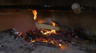 El, alfresk bir yaz yemeği için ızgara ateşinde yakacak odun ayarlıyor. Parlak ve parlak turuncu alevler ve ızgara altında parlayan közler. Bahçe pikniği partisi için ateş yakıyorum..