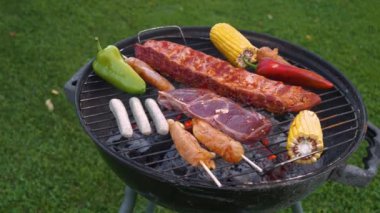 Mısır, pirzola, sosis, biber, tavuk şişi ve biftek gibi çeşitli baharatlı et ve taze sebzelerle dolu bir barbekü ızgarası. Barbekü partisinde nefis ızgara yemek..