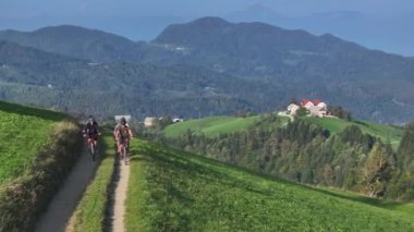 Bir dağ yolunda pedal çeviren bir grup genç bisikletçi, çarpıcı manzarası ve bereketli kırsal bölgeleriyle çerçevelenmiş. Güzel doğanın kucakladığı açık hava sporlarının heyecan verici deneyimi..