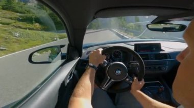 DOLOMITES, İtalya, 5. AĞUSTOS 2024: Petrolcü adam güneşli Dolomitler 'deki bir zaman denemesinde yeni BMW' sini kullanıyor. Kokpitte BMW spor arabasıyla dolambaçlı bir dağ yolunda yarışan bir adamın fotoğrafı var..