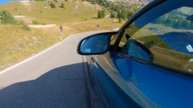 DOLOMITES, Italya, 5. AĞUSTOS 2024: Yaklaş: Mavi bir BMW M2 'nin İtalya' daki dolambaçlı dağ yolunda hız yaparken serin çekimi. Heyecan arayan beyaz adam güneşli Dolomitler 'de yeni spor yarasıyla yarışıyor..