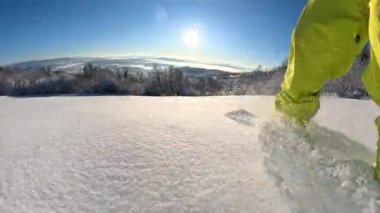 Düşük açılı, yakın mesafede, LENS FLARE: Snowboardcu yeni düşmüş toz kar sürüşü sevimli melez köpek eşliğinde güneşli bir Aralık günü güzel bir kırsalda yokuş aşağı koşuyor..