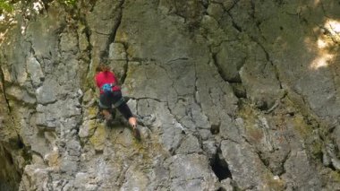 Sakin bir yaz gününde zorlu kireçtaşı uçurumuna tırmanan formda bir kadın dağcı. Atletik beyaz kadın açık havada dik kireçtaşı bir duvara tırmanıyor. Sportif kadın kayalık duvara tırmanıyor..