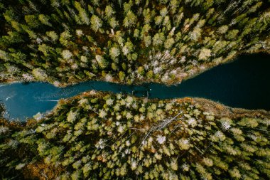 Aerial view of blue water river with suspension bridge and green woods in Finland.