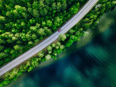Aerial view of coastline road with green woods and blue lakes water in summer Finland.