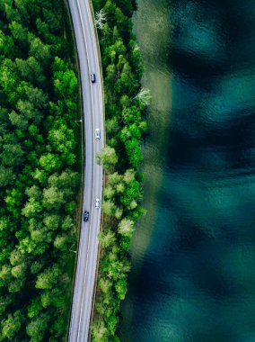 Aerial view of coastline road with green woods and blue lakes water in summer Finland.
